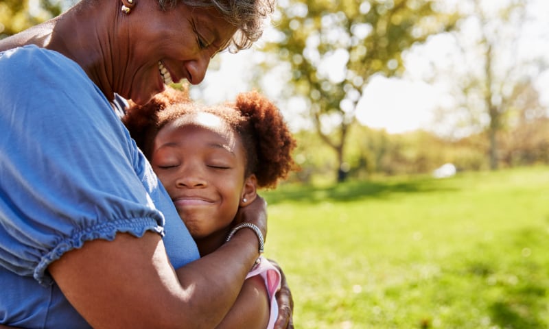 A Black grandmother holds a child close to her