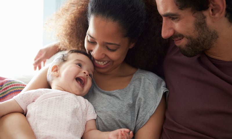 An interracial couple holds their baby