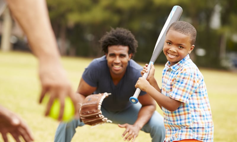 A young boy stands at bat, playing baseball