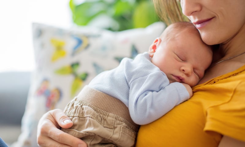 A mother holds her sleeping infant on her chest