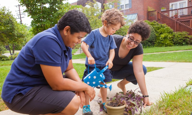 Two mothers with their son, watering plants