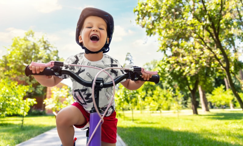 A young boy happily rides his bike