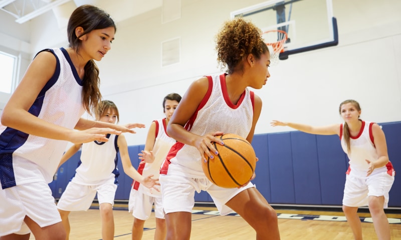 Teen girls play a game of basketball